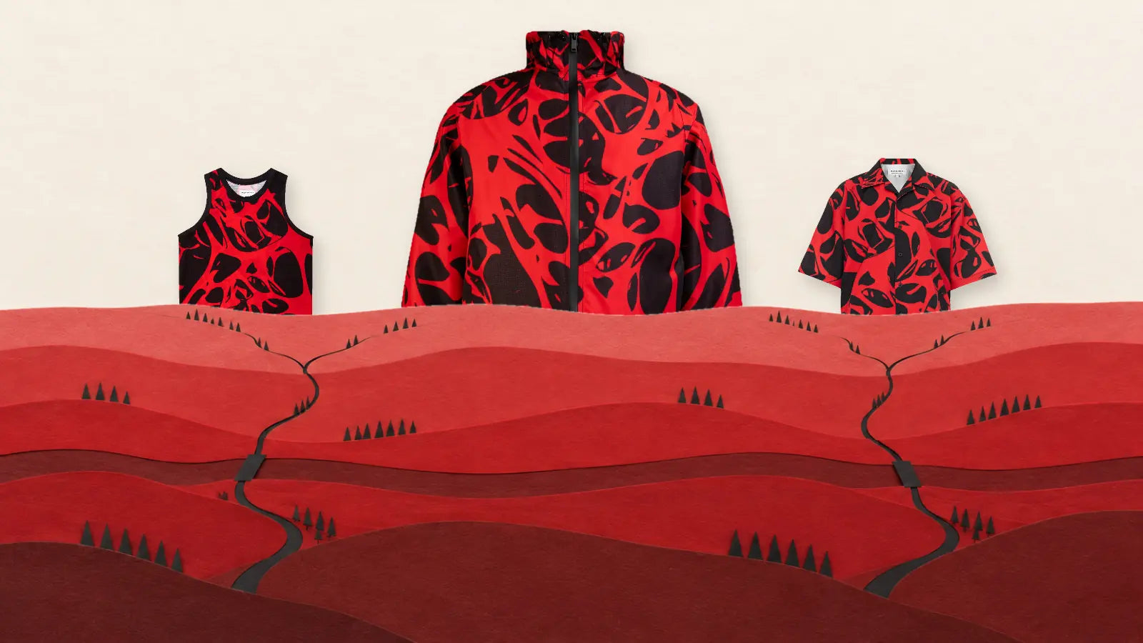 Tre capi Strand Red dietro l'orizzonte di una valle di carta rossa, sotto un cielo di carta chiara. Al centro la giacca a vento, la più alta, a sinistra la canotta, a destra la camicia a maniche corte, tutti con la stessa stampa rossa e nera. Le colline, in più file, ne coprono la parte bassa. Nella valle due sentieri neri che si dividono, due ponti di carta su un fiume rosso scuro e file di alberi neri a cono.