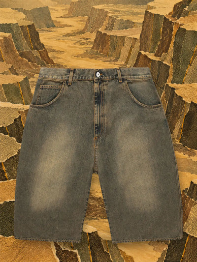 The brown Aged denim shorts in a canyon of ochre and olive paper.