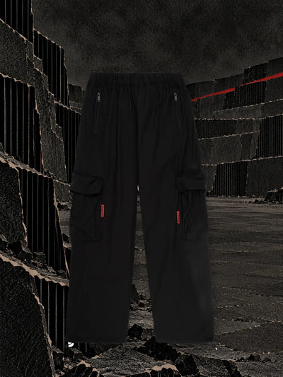 The black cargo trousers in a terraced quarry of black corrugated cardboard, with a strip of red tape along the top edge.