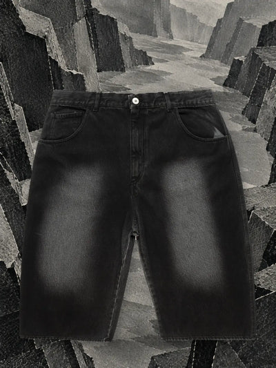 The faded black denim shorts in a canyon with walls of black and grey paper.