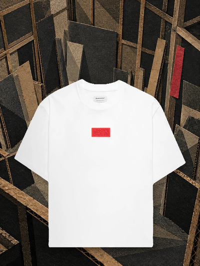 La t-shirt bianca Deconstructed in un laboratorio di cartone lasciato a metà, fra travi e pannelli appoggiati.
