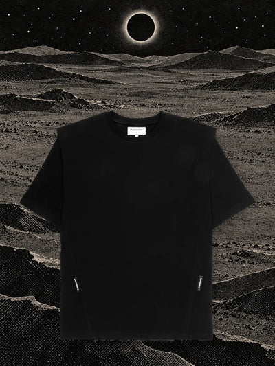 La t-shirt nera Eclipse su colline di carta nera, sotto un'eclissi con un anello di luce bianca.