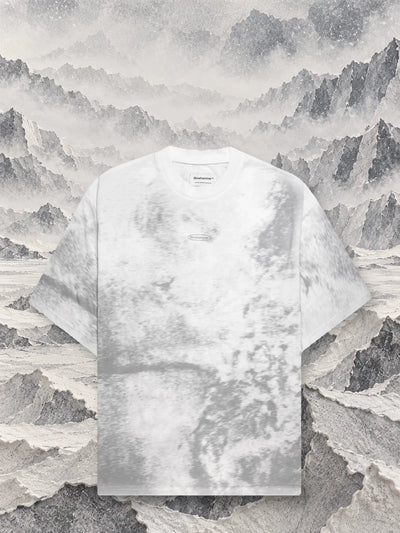 La t-shirt grigia Grey Noise davanti a creste di carta grigia e bianca che sfumano nella nebbia.