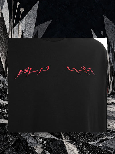 Un pezzo del petto della t-shirt nera Insectide, con la scritta rossa, appeso a un filo fra lame di carta nella notte.