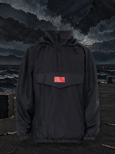 L'anorak nero Not Required su un molo di carta, davanti a onde di carta nera sotto un cielo in tempesta.