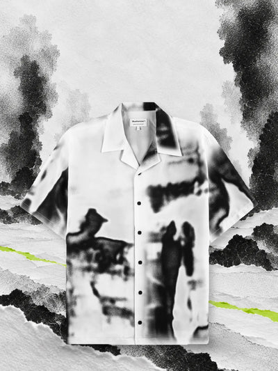 La camicia a maniche corte bianca e nera Rift sulla neve di carta, fra colonne di fumo nero.