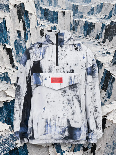 L'anorak bianco Rugged fra pareti di carta strappata bianca e blu.