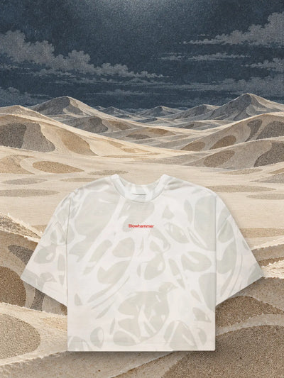 La t-shirt corta avorio Strand Ivory sopra dune di carta avorio e sabbia.
