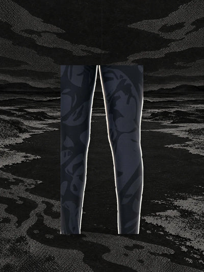 Un pezzo della stampa dei leggings neri Strand, appeso a un filo sopra la riva di un fiume di carta nera.
