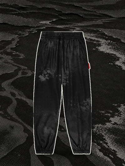 The black Strand joggers, with a pale paper border, on the bank of a river of black halftone paper.