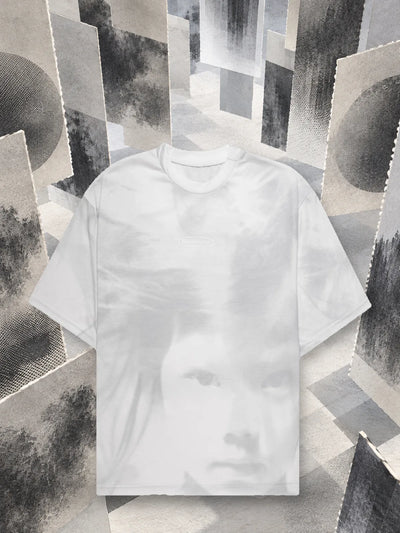 La t-shirt bianca Stream fra pannelli di carta grigia appesi, stampati a retino.