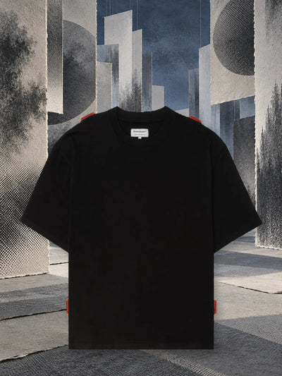 La t-shirt nera Stream fra pannelli di carta grigia appesi, nella penombra.