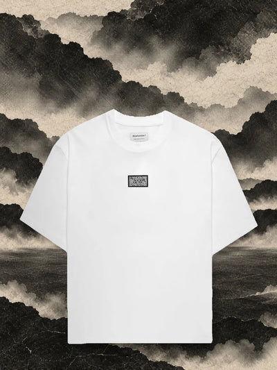 La t-shirt bianca Triodrome fra pannelli di carta scura, sotto un cielo di fumo di carta grigia.